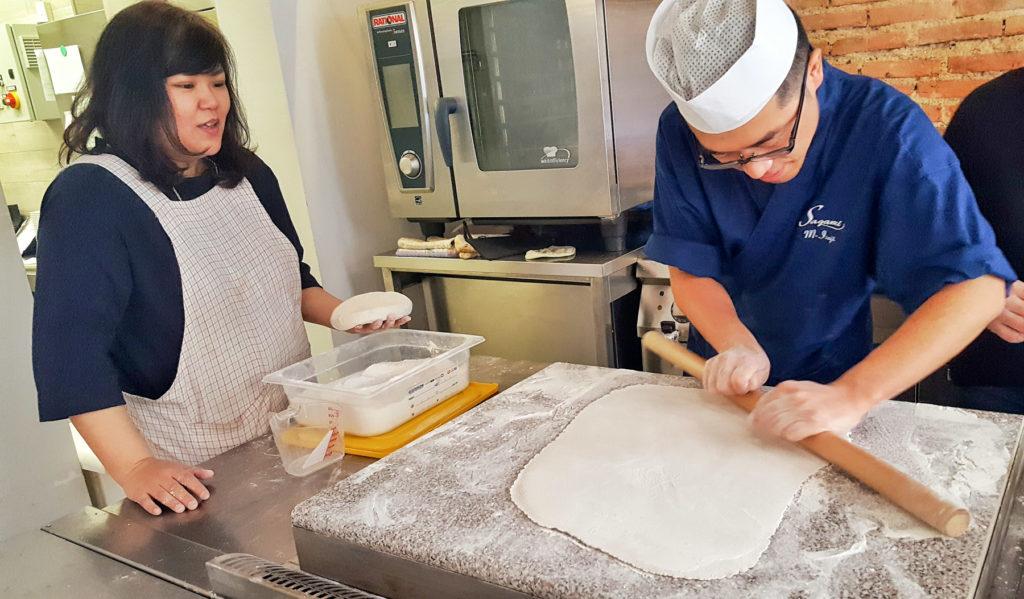 Arrotolare la pasta sul mattarello e farla scivolare sul piano imprimento una leggera pressione per tre volte, poi srotolare e ripetere nell'altro senso.